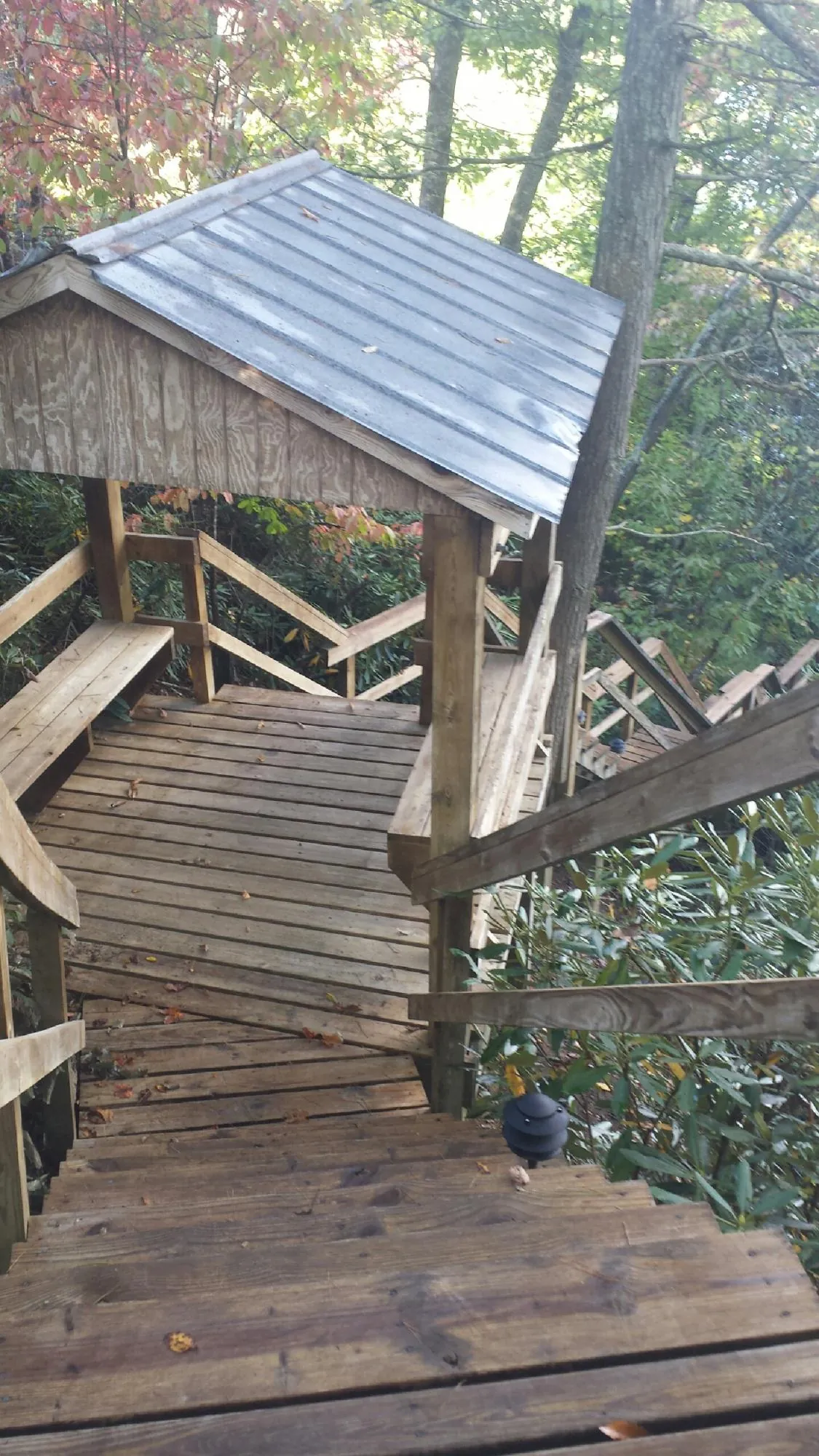Metal roofed shelter over wooden steps on a wooded walkway — Skylight Repair & Installation work by our crew in Devol