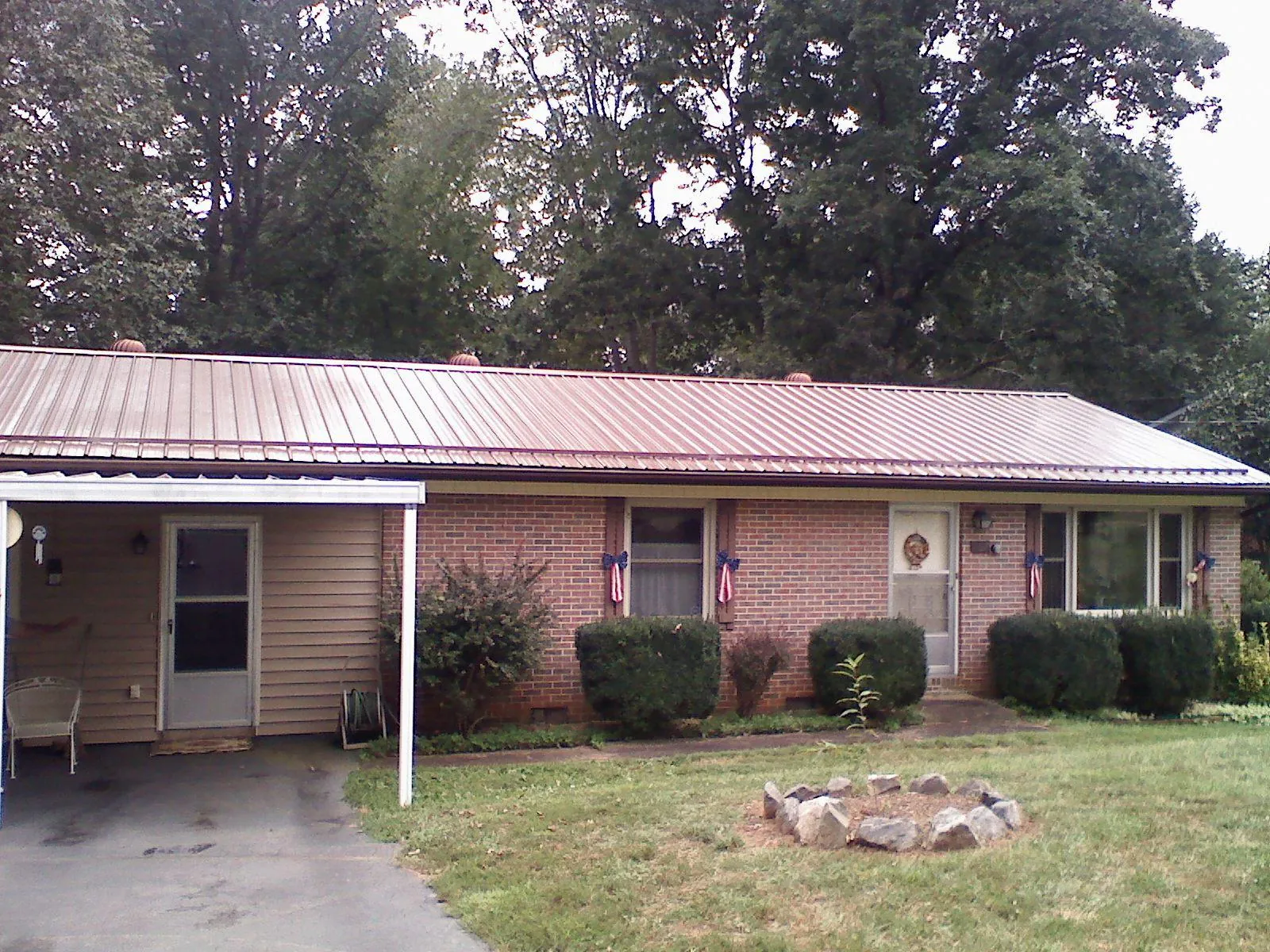 Bronze metal roof and carport on a brick ranch home — Roof Repair work by our crew in Devol
